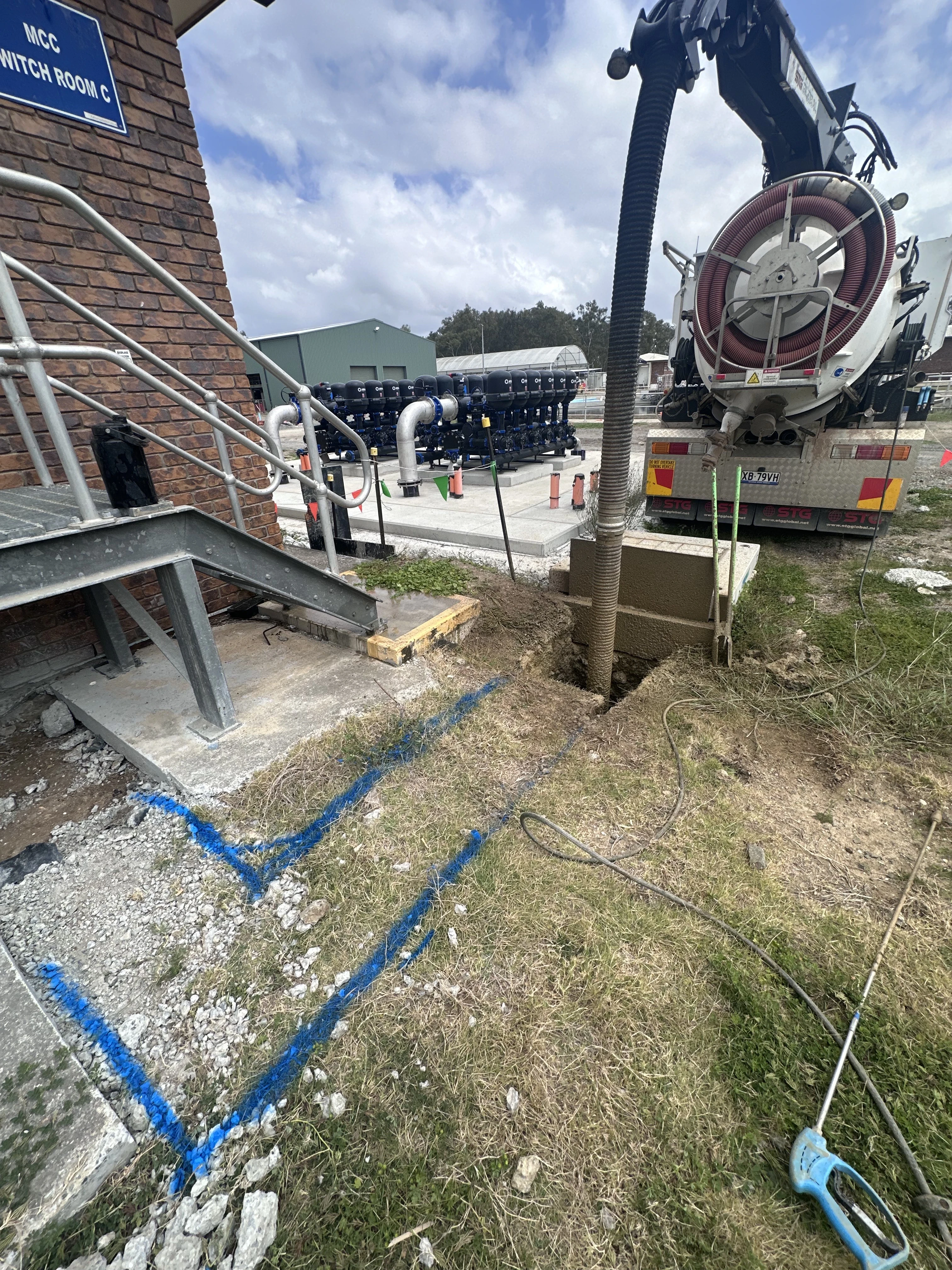 Vacuum excavation site showing a vac truck and excavation pit with exposed underground pipes